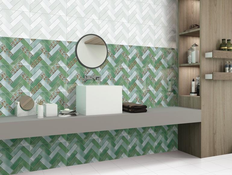 A modern green bathroom design with herringbone tiles, a floating vanity, a round mirror, and shelves.